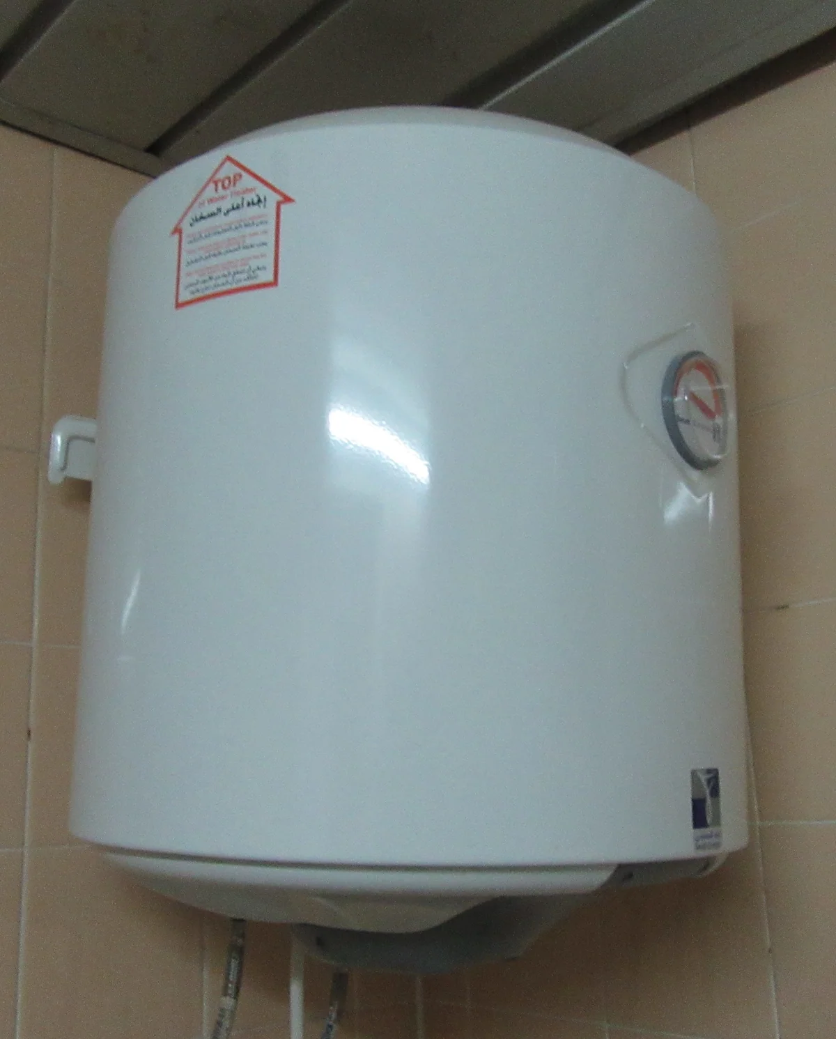 Termo eléctrico compacto blanco en una estancia alicatada. Imagen de archivo.