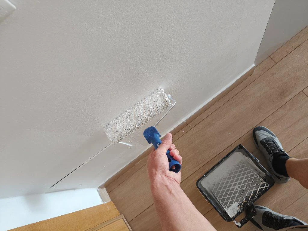 Aplicación con rodillo de pintura blanca en una pared de vivienda