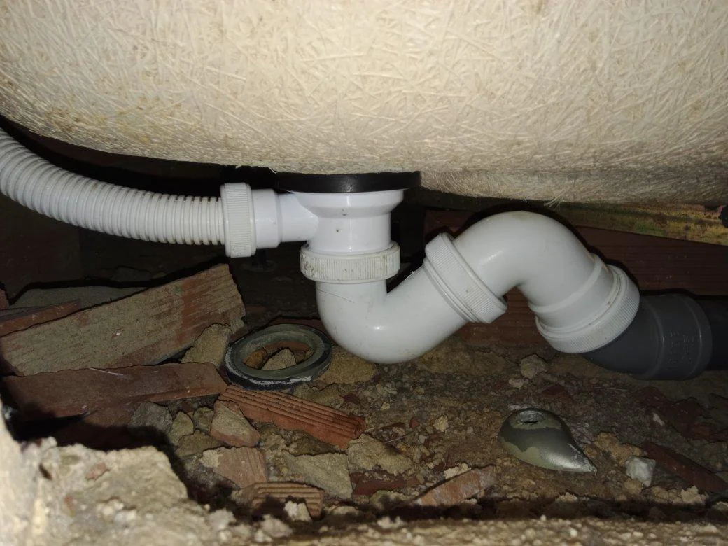 Conjunto de evacuación conectado bajo una bañera durante su reparación