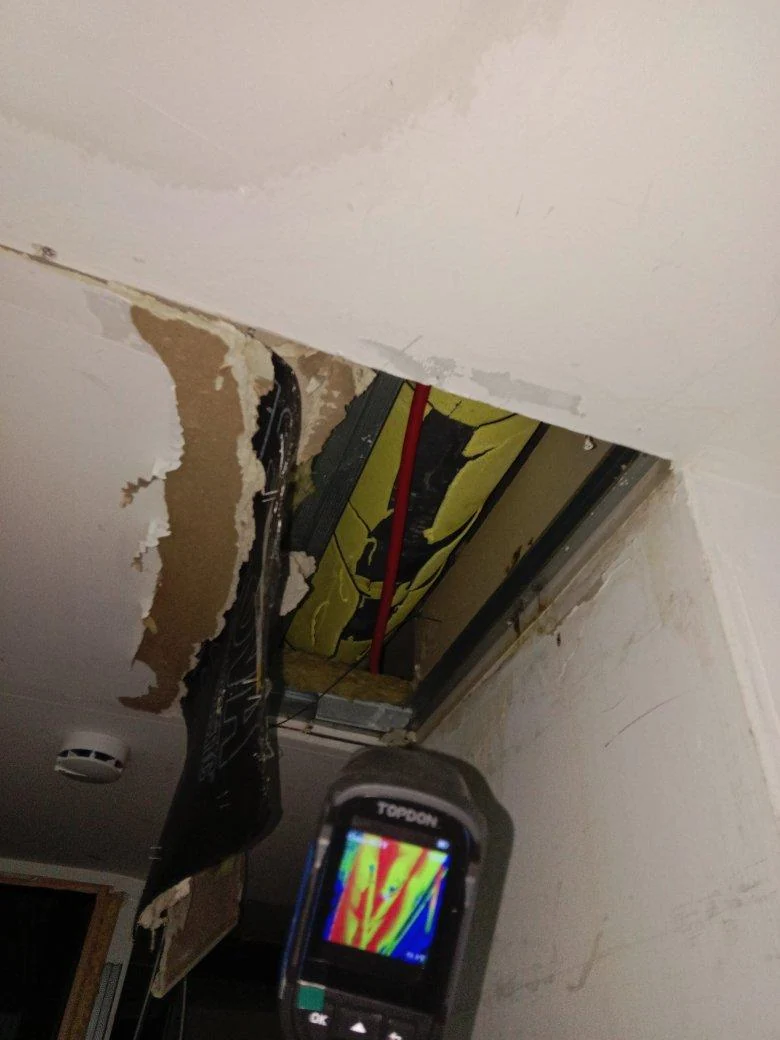 Apertura en un falso techo y pantalla de equipo de termografía durante la inspección