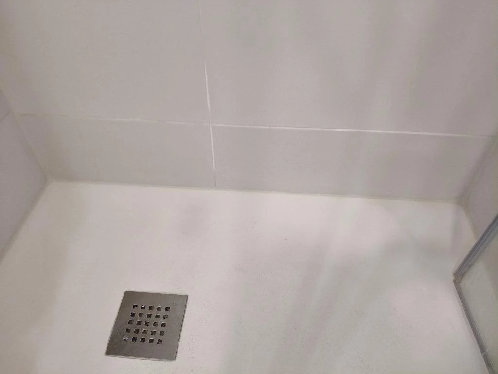 Azulejo blanco repuesto junto al plato de ducha