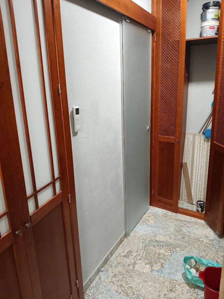 Pared gris junto a una puerta corredera después de los trabajos de acabado