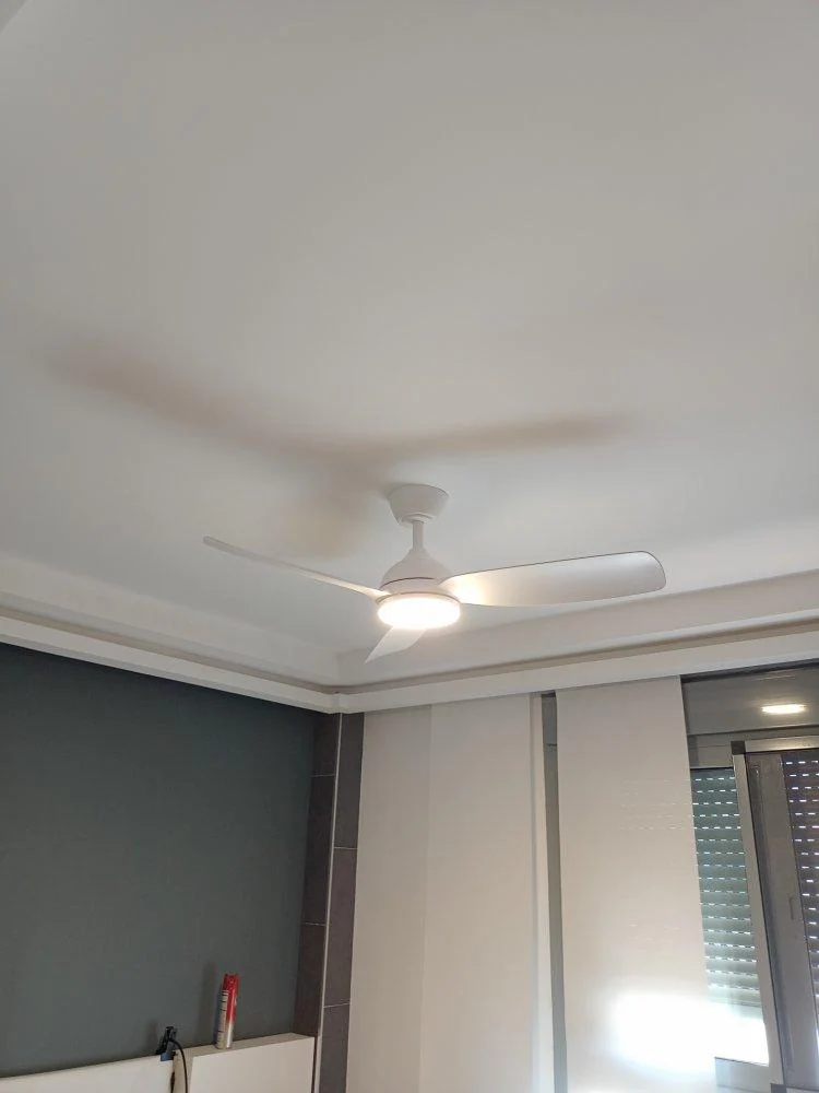 Ventilador blanco de techo con la luz encendida